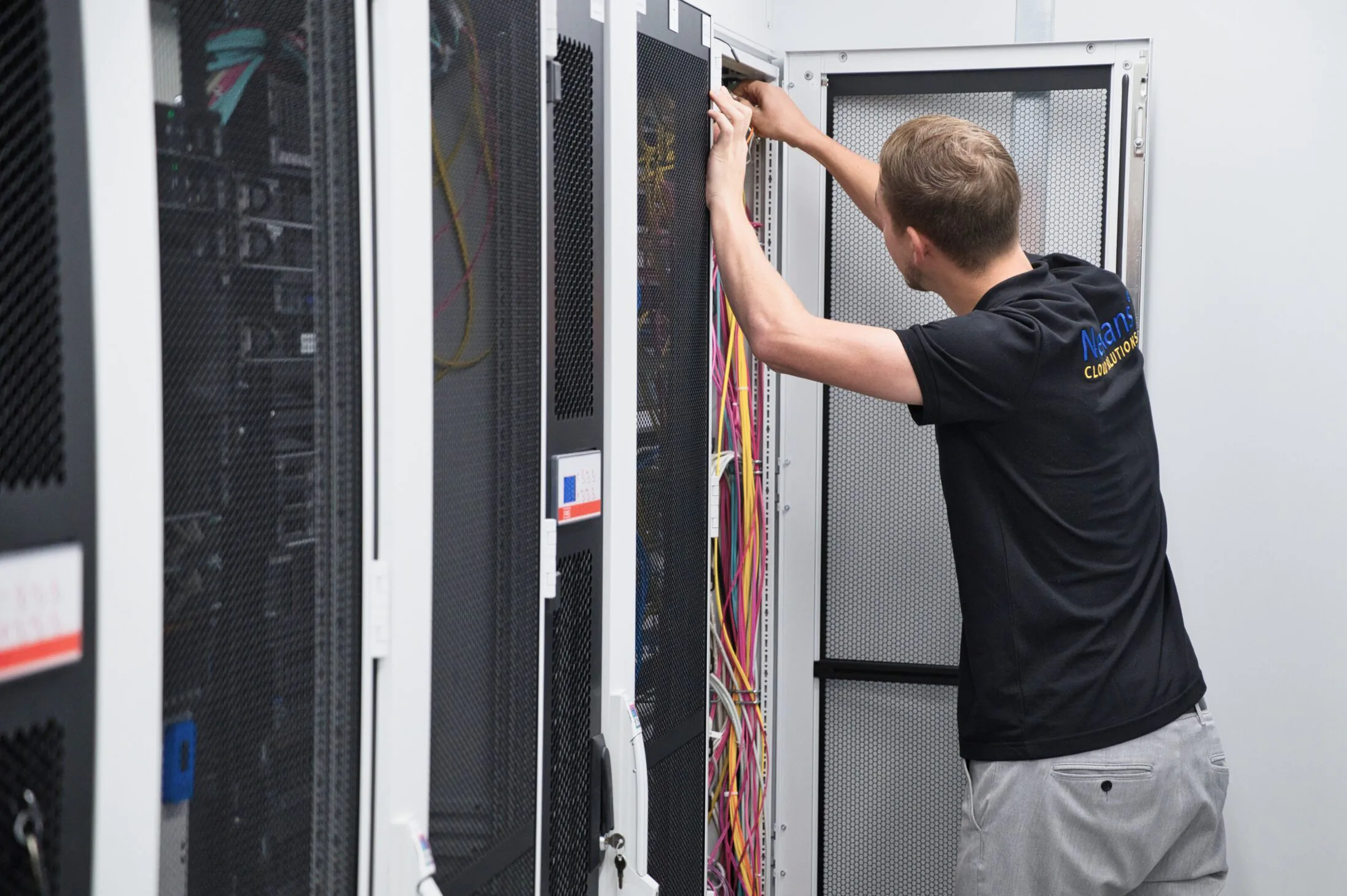 stehender junger Techniker installiert Kabel am Serverschrank